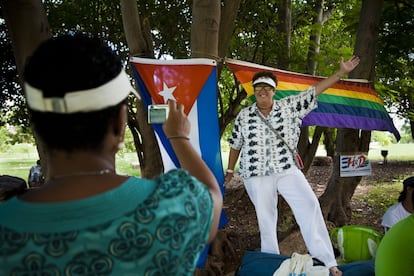 Esta es una muestra del trabajo de la fotógrafa Nuria López Torres dentro su proyecto 'Sex and Revolution in Cuba' que ha desarrollado a lo largo de tres años y en el que documenta la vida de la comunidad LGTBI en aquel país. Lo ha hecho en un período en el que la isla experimenta importantes cambios sociopolíticos, uno de ellos relacionado con las nuevas políticas de sensibilización en materia de diversidad sexual e identidad de género que lidera Mariela Castro, hija del actual presidente y directora del Centro Nacional de Educación sexual de Cuba. Este viraje respecto a gais, lesbianas y transexuales ha sido interpretado por algunos como una simple estrategia de marketing en materia de Derechos Humanos. <p>En la imagen, Miranda, de 42 años, hace una foto a su pareja, Mercedes, de 52, junto a la bandera cubana y la del orgullo gay en una actividad al aire libre del grupo Hombres por la Diversidad. Mercedes es una activista por los derechos de la comunidad LGTBI en Cuba. Dejó su exitosa carrera como militar a los 30 años porque ya no podía ocultar más su condición de lesbiana. Ella era la traductora personal de Raúl Castro, traducía del ruso cuando llegaban las delegaciones militares de Rusia a Cuba. Hoy, vive su relación con Miranda de forma abierta y se encuentra vinculada al Centro Nacional de Educación Sexual de Cuba.</p>