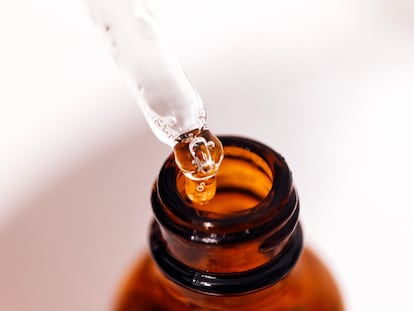 Close up of brown serum or oil glass with mock up on bottle on mirror background. Drops of liquid in a pipette. Concept of natural organic cosmetic and beauty, cosmetology, dermatology.