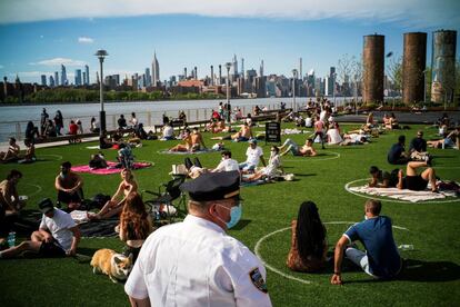 Un agente de la policía de Nueva York vigila a las personas que disfrutan de un día soleado en Domino Park de Brooklyn.