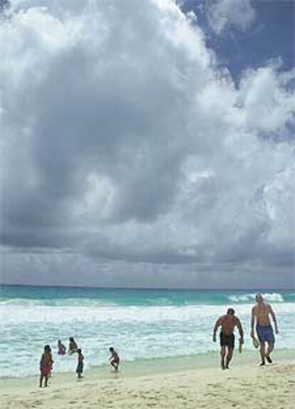 Varios turistas salen del agua mientras la tormenta se aproxima a las playas de Cancún.