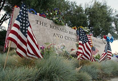 Flores y banderas, ante el letrero de entrada a la biblioteca Ronald Reagan en Simi Valley (California).