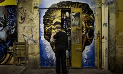 Un comerciante cierra las puertas de su establecimiento en el mercado Mahane Yehuda, decorado con un grafiti del artista callejero Solomon Souza, en Jerusalén.