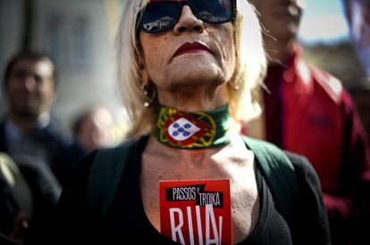 Una mujer que protesta ante el Parlamento lleva un cartel donde se lee &quot;Passos y la Troika, fuera&quot;. 