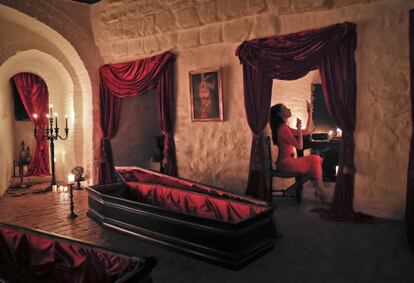 Tami Varma, granddaughter of Devendra Varma, a scholar of English gothic tales and an expert in vampire lore, adjusts her makeup at the Bran Castle, in Bran, Romania, Monday, Oct. 31, 2016. A Canadian brother and sister are passing Halloween night curled up in red velvet coffins in the Transylvanian castle that inspired the Dracula legend, the first time in 70 years anyone has spent the night in the gothic fortress, after they bested 88,000 people who entered a competition hosted by Airbnb to get the chance to dine and sleep at the castle in Romania. A portrait of medieval prince Vlad the Impaler is placed on the wall. (AP Photo/Vadim Ghirda)