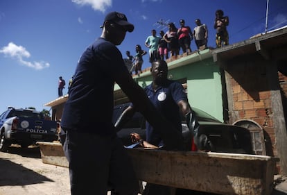 Residentes del barrio de Sao Cristovao, observan como la policía forense se lleva el cuerpo de una persona asesinada a tiros por la noche en Salvador de Bahía (Brasil).