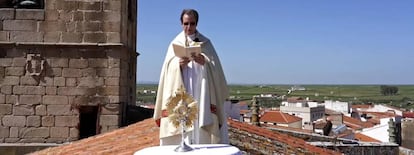 El párroco de Arroy de la Luz (Cáceres) bendice el pueblo desde el tejado de la iglesia.