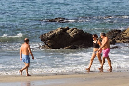 Varias personas pasean este jueves de otoño por la playa de Samil.