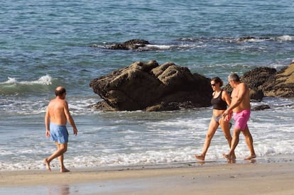 Varias personas pasean este jueves de oto&ntilde;o por la playa de Samil.