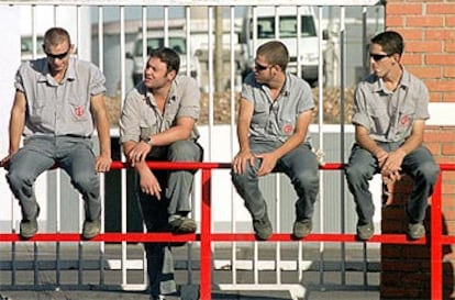 Cuatro jóvenes trabajadores subcontratados, sentados en una valla de la refinería de Puertollano.