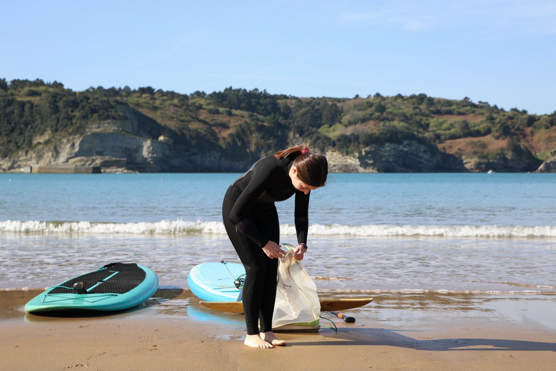 Idoia Fuertes, investigadora de Surfrider, amarra una red barredera a la tabla de pádel-surf.