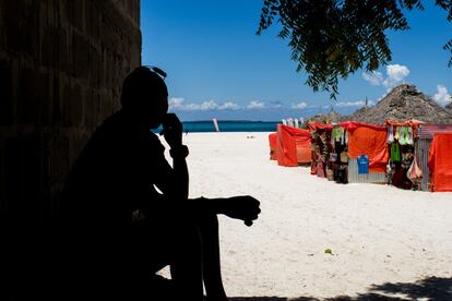 Unguja y Pemba, las dos islas de Zanzíbar, están a unos 80 kilómetros mar adentro del país al que pertenece: Tanzania. Y necesitan el turismo. Representa un 27% de su PIB y genera unos 50.000 empleos directos y otros 150.000 indirectos. Entre 1984 y 2014 pasó de 20.000 a más de 300.000 visitantes. Y pretenden llegar al medio millón en 2020. En la imagen, el dueño de una tienda de comestibles en la playa de Nungwi, en el norte de Unguja, descansa a la sombra. Al fondo, puestos de recuerdos gestionados por masais y destinados a los turistas que visitan este lugar.