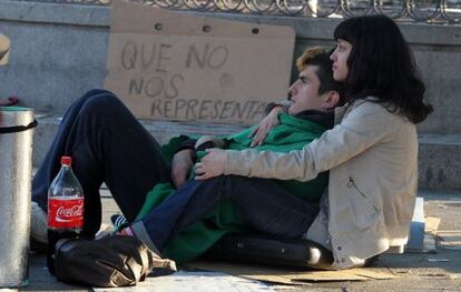 Dos jóvenes en la Puerta del Sol en mayo con una pancarta con el lema "Que no nos representan".