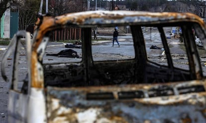 Un hombre camina por una calle de Bucha, al noroeste de Kiev, con varios cadáveres en el suelo, el sábado.