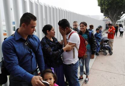Un grupo de migrantes espera a cruzar la frontera de Estados Unidos para comenzar el proceso de solicitud de asilo, entre Tijuana y San Ysidro.