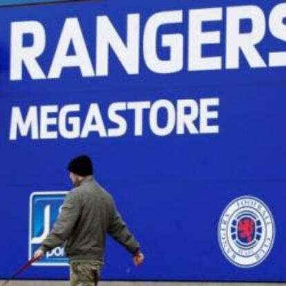 Un hombre pasa por la puerta de la tienda del estadio de Ibrox Park, casa del Glasgow Rangers.