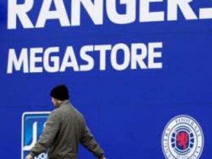 Un hombre pasa por la puerta de la tienda del estadio de Ibrox Park, casa del Glasgow Rangers.