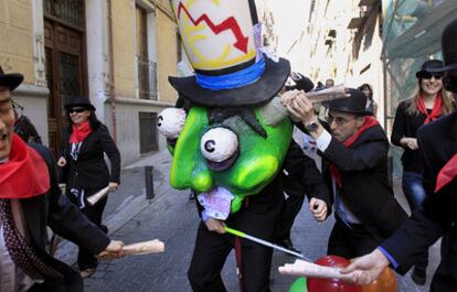 Un corredor agarra un cuerno del cabezudo que representa a la crisis, durante el encierro por el Día de la Diversión en el Trabajo.