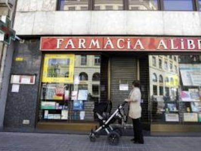 Una mujer contempla la fachada de una farmacia cerrada en el centro de Barcelona durante la huelga que secundaron masivamente para reclamar a la Generalitat y al Estado el pago que se les adeuda. EFE/Archivo