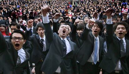 Un grupo numeroso de estudiantes universitarios levantan sus puños cerrados durante una ceremonia para conseguir empleo en el parque Hibiya de Tokio (Japón).