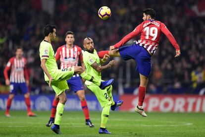 El delantero español del Atlético de Madrid, Diego Costa salta ante Arturo Vidal y Sergio Busquets.