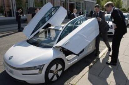 Un trabajador abre las puertas de un Volkswagen XL1 antes de la inauguración de la Conferencia Internacional de Electromovilidad en Berlín (Alemania). EFE/Archivo
