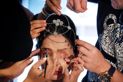 Los maquilladores y peluqueros dan los últimos retoques a Reshma Quereshi antes de salir a la pasarela.