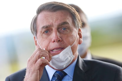 O presidente Jair Bolsonaro remove sua máscara para conversar com apoiadores