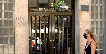 Una mujer pasa frente a un edificio con un piso en venta, en Madrid.