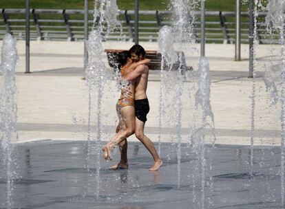 Dos jóvenes se refrescan en una de las fuentes del parque Juan Carlos I.