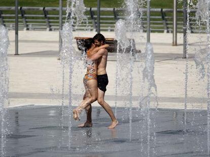 Dos jóvenes se refrescan en una de las fuentes del parque Juan Carlos I.