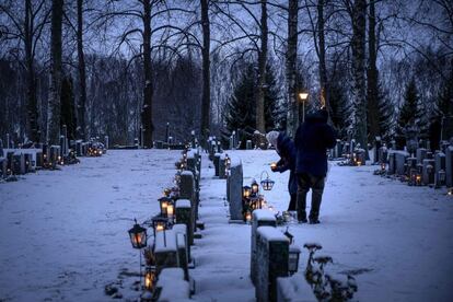 Varias personas colocan velas junto a las tumbas en un cementerio en Vaasa (Finlandia), el 24 de diciembre de 2018. 