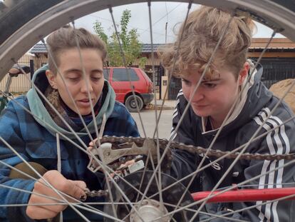 Dos colaboradores del Taller de Bicis del Vecindario, reparan la cadena de una bicicleta, en Córdoba (Argentina)