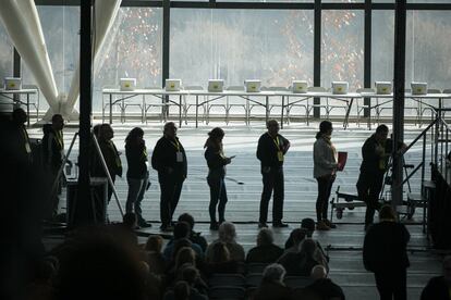Un grup de participants a l'assemblea esperen el seu torn per poder parlar. Al fons de la imatge, les urnes preparades per a les votacions.
