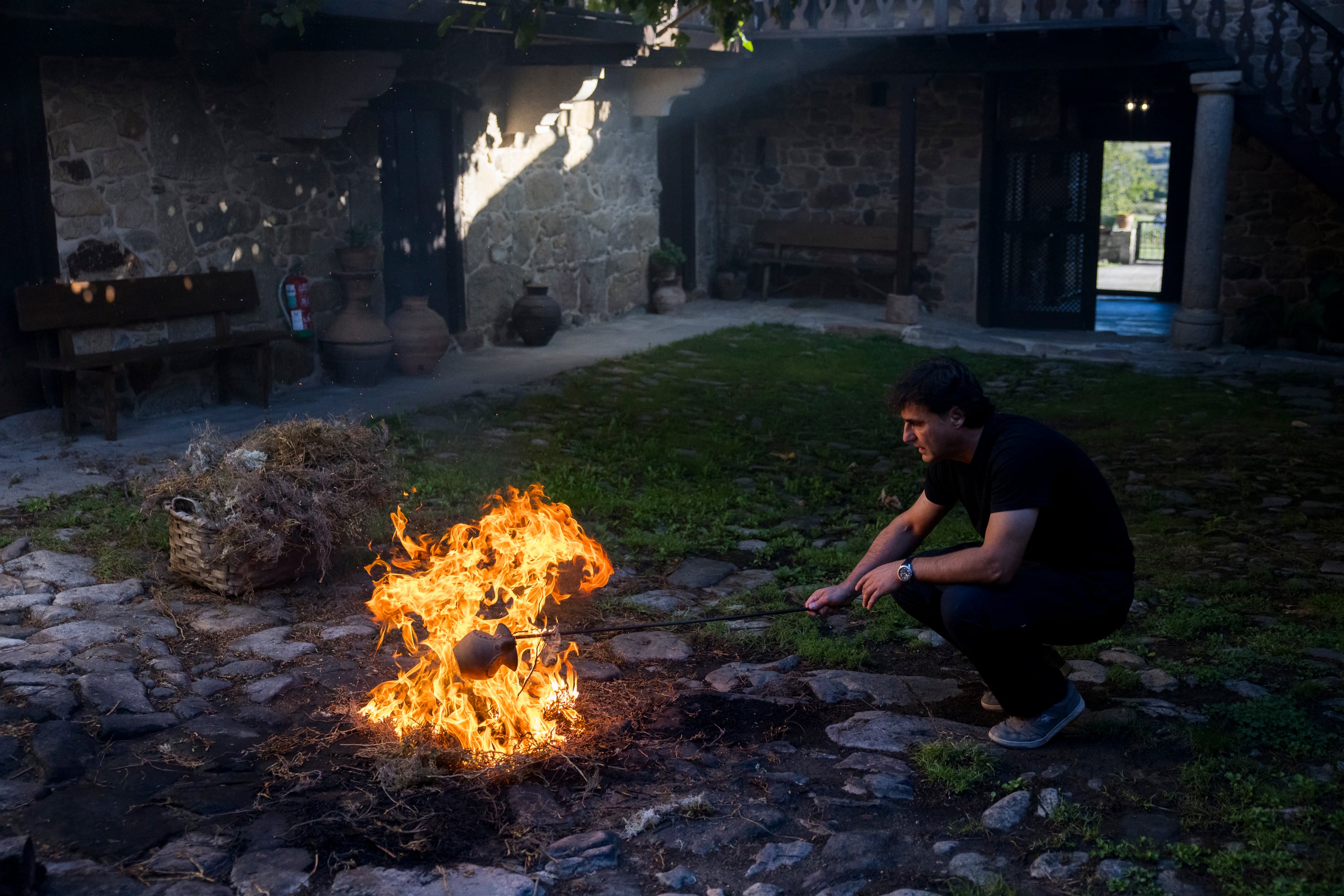 El alfarero Elías González calienta una pieza de barro para someterla después al proceso de empegado con resina para impermeabilizarla.