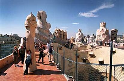 Turistas en la terraza barcelonesa de La Pedrera o Casa Milà, de Gaudí, rodeados por escultóricas chimeneas modernistas.