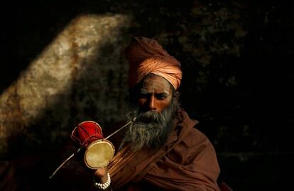 Un santo hindú, o sadhu, toca un tambor en el templo de Pashupatinath la víspera del festival Shivaratri en Katmandú (Nepal), el 12 de febrero de 2018.