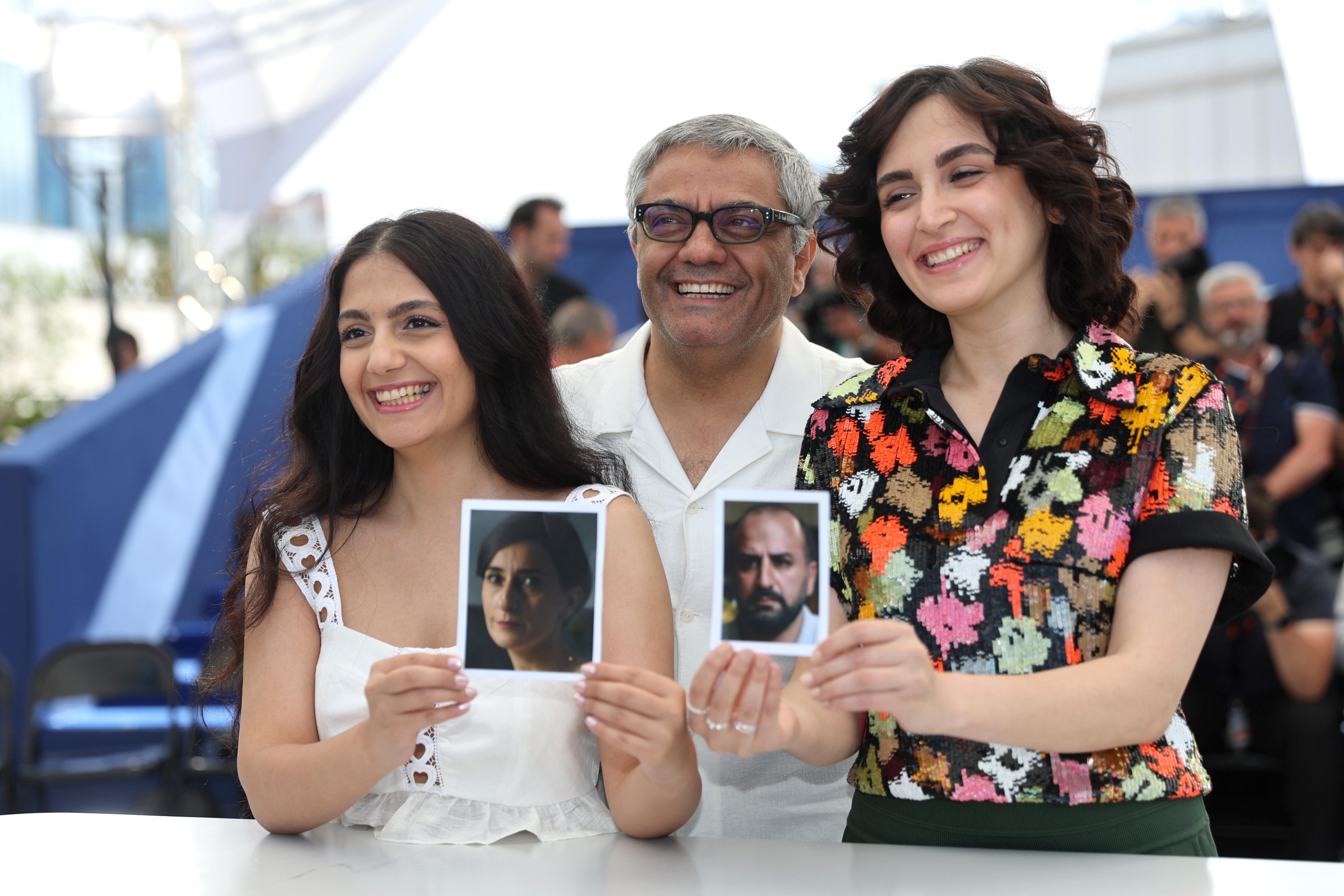 Las actrices Mahsa Rostami (derecha) y Setareh Maleki (izquierda) muestran fotos de los actores que encarnan a sus padres, Missagh Zareh y Soheila Golestani, junto al director Mohammad Rasoulof, la mañana del sábado en Cannes.