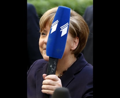 Angela Merkel con un micrófono que se le había caído al suelo a un periodista durante la cumbre de los líderes de la Unión Europea, en Bruselas, para tratar la crisis de Ucrania.
