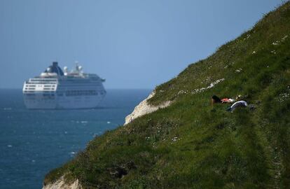 Una pareja observa las vistas desde un acantilado mientras un crucero navega por el Canal de la Mancha cerca de West Lulworth (Reino Unido).