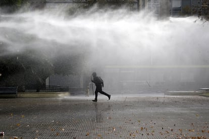 Un estudiante chileno intenta huir del cañón de agua que la policía lanza para disuadir la manifestación convocada este jueves a favor de una mejor educación pública.