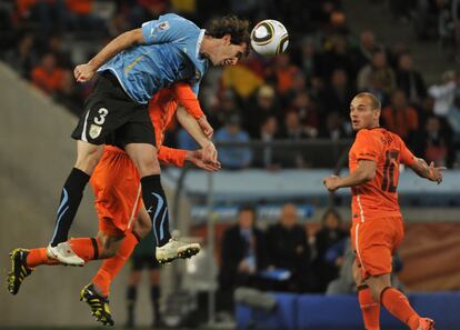 El defensa uruguayo Diego Godin remata de cabeza en presencia del holandés Wesley Sneijder.