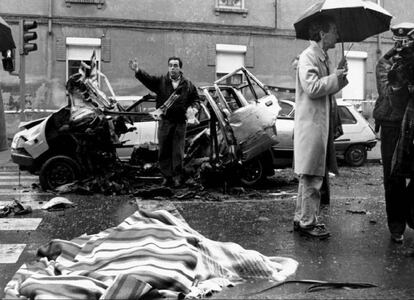 El cadáver del comandante Cortizo, cubierto por una manta, junto al coche destrozado por la bomba lapa.