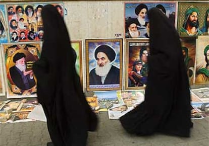 Dos mujeres vestidas con abayas pasan delante de un retrato del líder religioso chií Alí al Sistaní, en un barrio bagdadí.