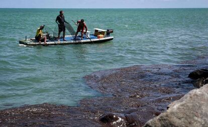 Pescadores recolhem óleo na praia de Janga, em Paulista, Pernambuco.