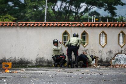 Oficiales de la Policía Municipal de Sucre se protegen durante enfrentamientos entre manifestantes y civiles no identificados en Caracas, Venezuela.