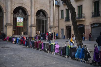 Carritos colocados en fila por sus dueños que esperan recibir un paquete semanal de alimentos y suministros donados, frente a una iglesia en Barcelona. Las solicitudes de alimentos han aumentado considerablemente desde el estallido de la pandemia.