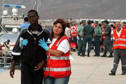 Una enfermera de la Cruz Roja conduce al hospital de campaña a uno de los 17 inmigrantes rescatados.