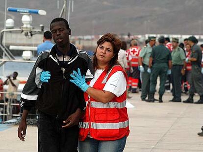 Una enfermera de la Cruz Roja conduce al hospital de campaña a uno de los 17 inmigrantes rescatados.