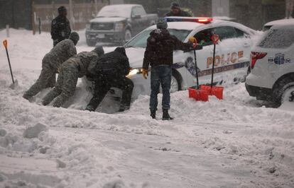 La costa este de Estados Unidos se enfrenta a una gran tormenta que durará al menos 36 horas y dejará entre 30 y 71 centímetros de nieve con vientos de hasta 96 kilómetros por hora, lo que obligó a declarar la situación de emergencia en seis estados. En la imagen varias personas intentan mover  un coche de policía atascado por la nieve en Washington.