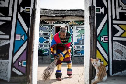 La artista sudafricana Esther Mahlangu, de 81 años, barre el suelo de su casa en Mpumalanga (Sudáfrica).